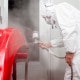 Man in a paint booth custom spray painting a car part