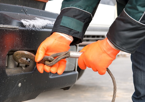 Gloved hands hooking a tow rope to a vehicle